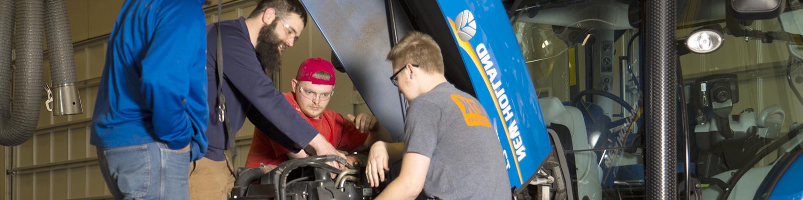 Group of students looking at engine under hood of tractor